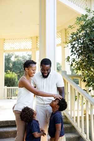 A happy family shares joyful moments together on a white porch during a sunny day.