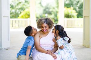 A tender family moment shared on a white porch with children showing affection.