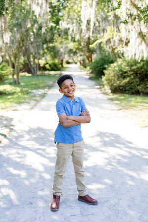 A youth in blue polo and khakis stands confidently on an outdoor path.