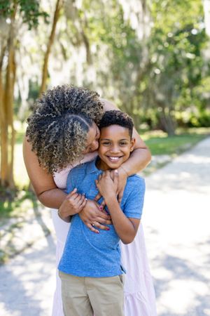 A joyful embrace shared between parent and child on a sunny outdoor path.