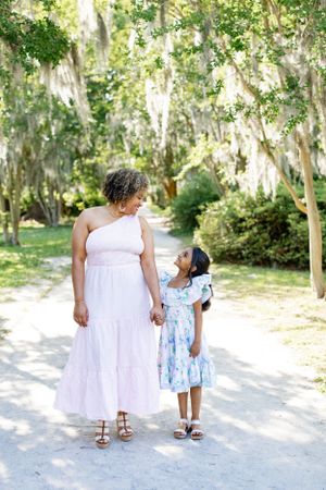 Parent and child sharing a sweet moment while holding hands on a sunny nature path.