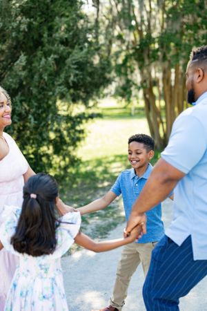 A family plays ring-around-the-rosy on a sunlit nature trail.