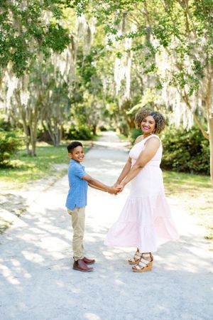 Two people hold hands while enjoying a moment on a garden path.