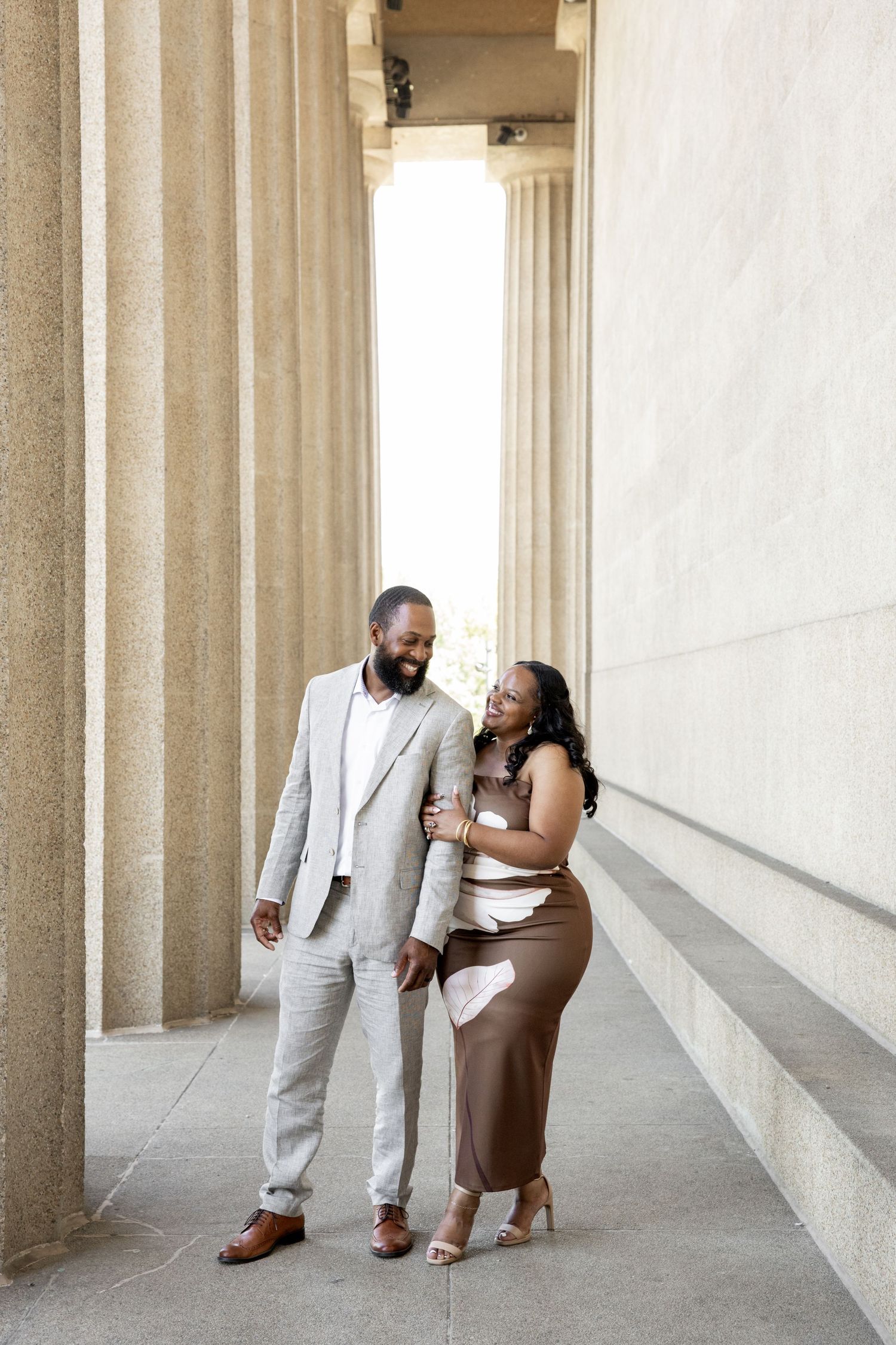 A couple dancing and twirling between classical white columns on a sunny day.