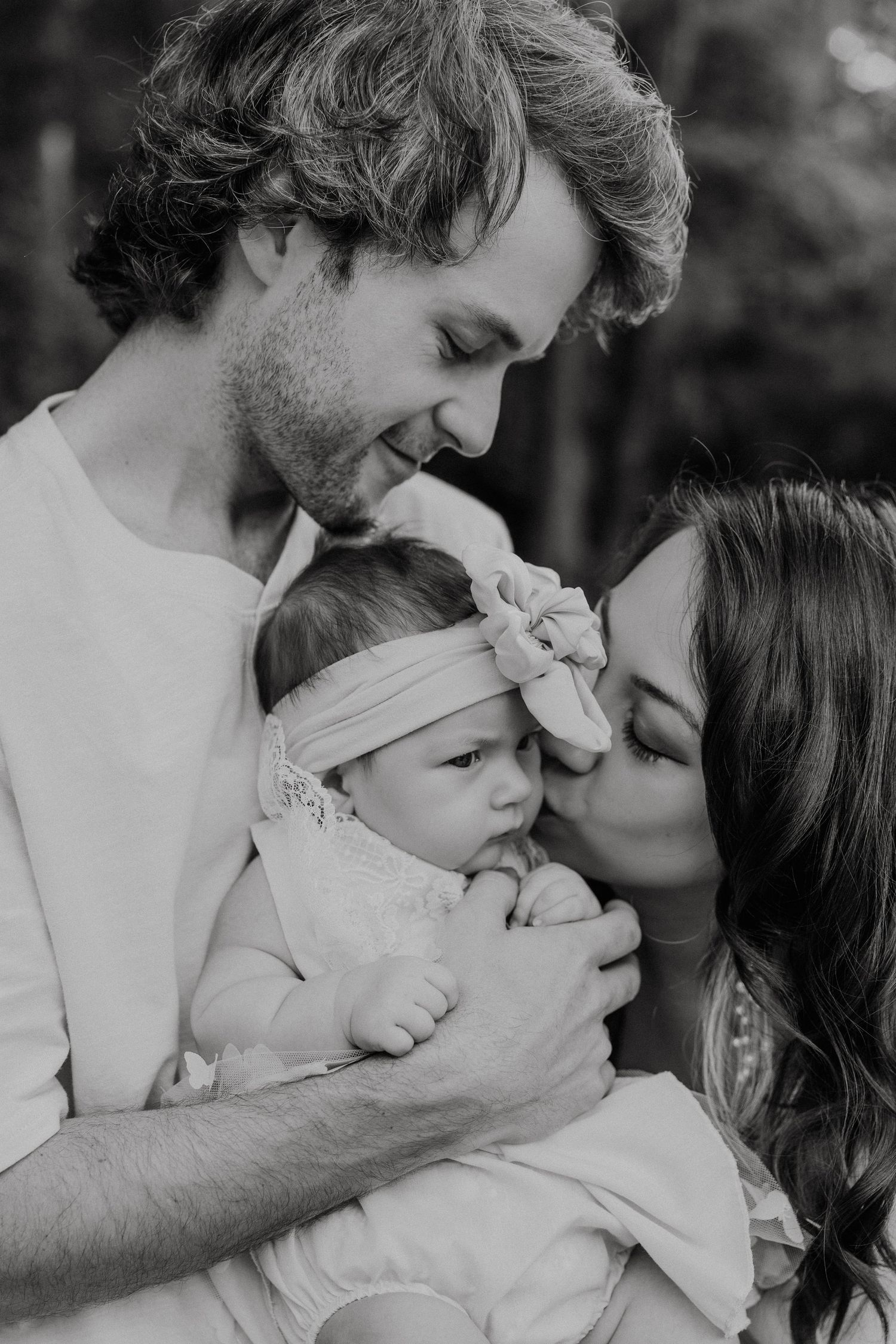A series of intimate black and white photos showing tender moments between a couple and their baby.