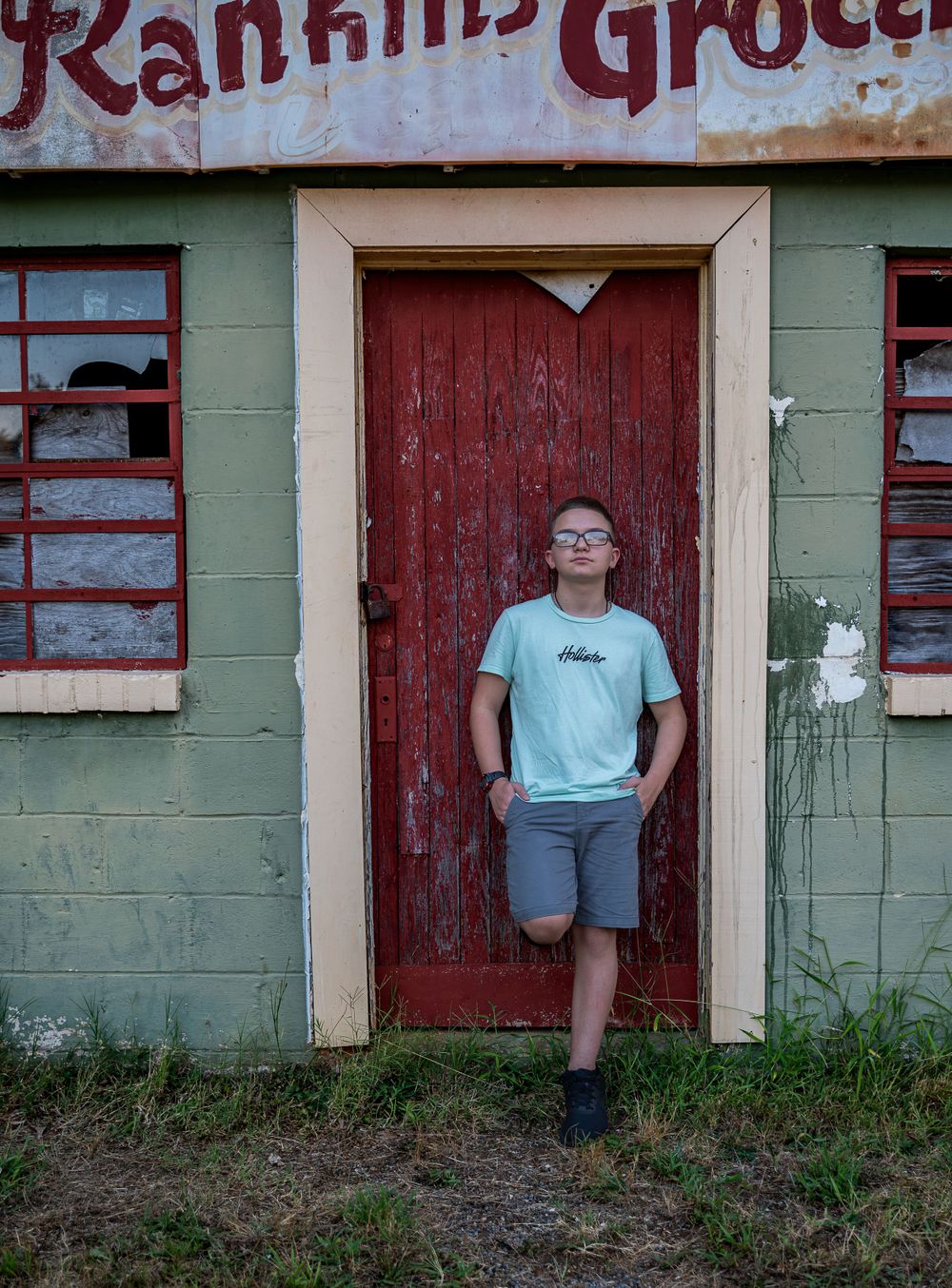Teen boy leaning on door in front of vintage grocery, Rankin's Grocery, Anderson, South Carolina