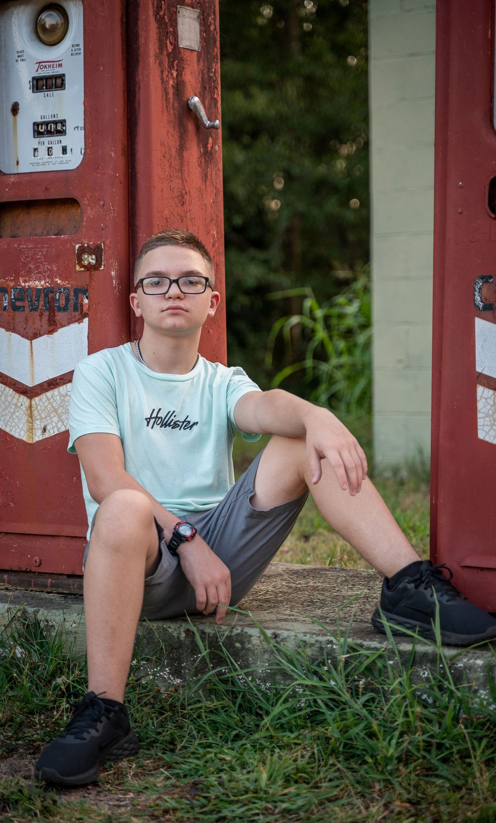 Teen boy sitting by gas pump in front of vintage grocery, Rankin's Grocery, Anderson, South Carolina