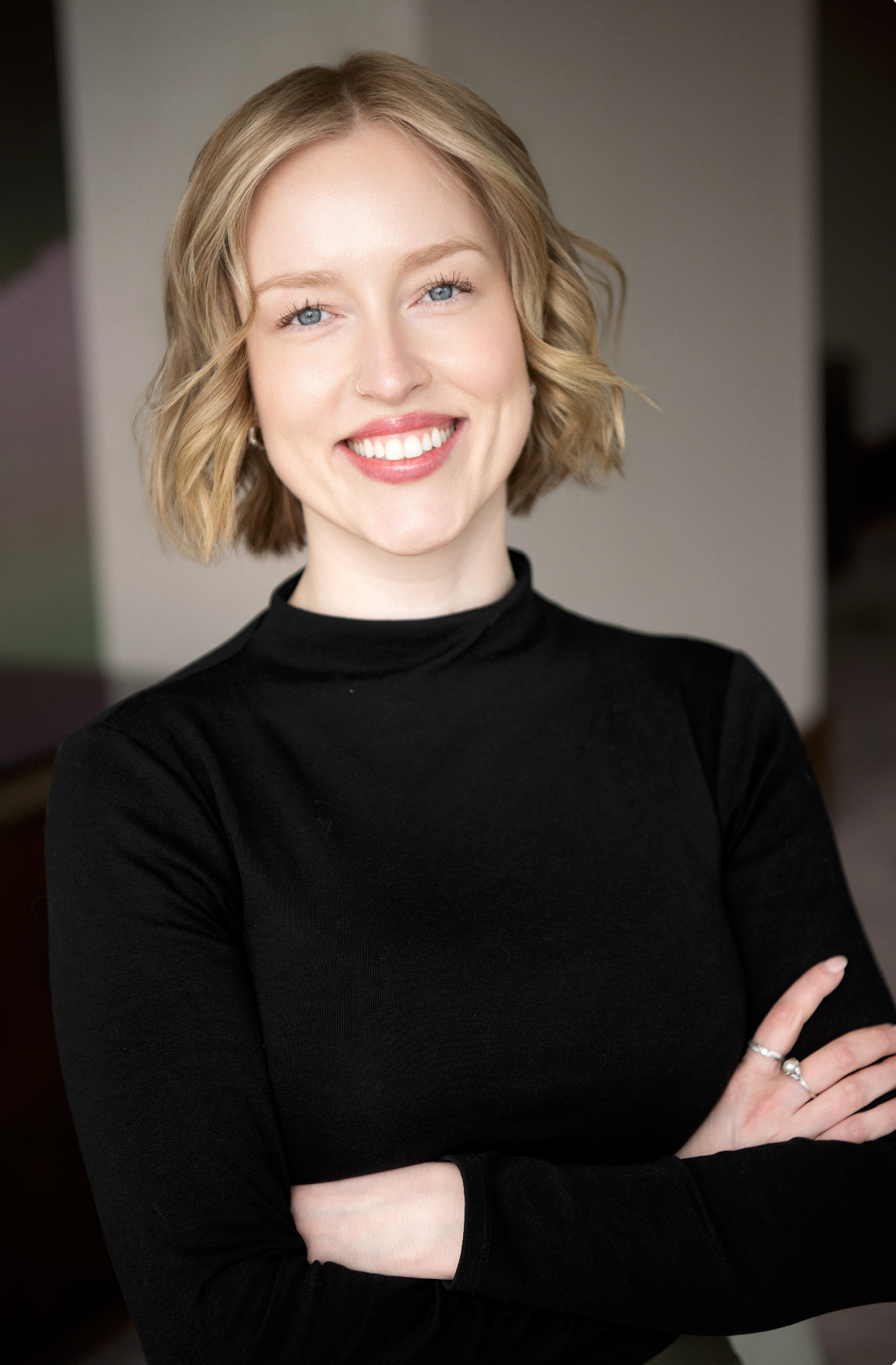 Business portrait of someone wearing black top with white skirt and designer belt.