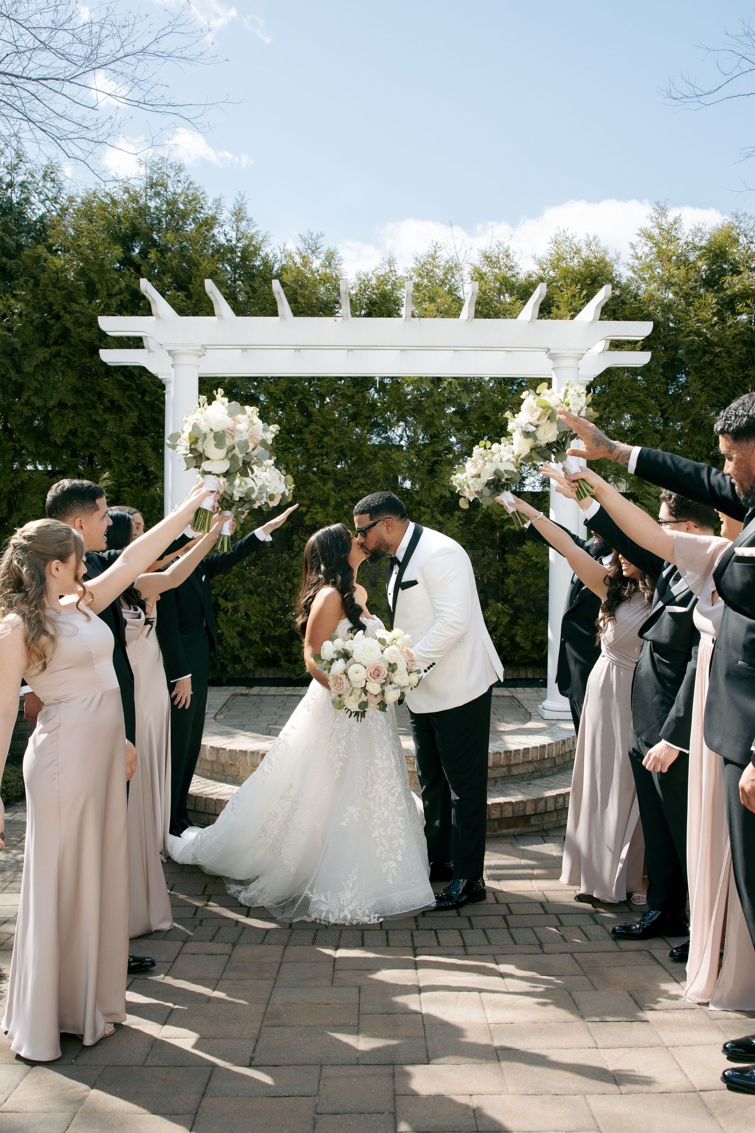 Elegant wedding couple posing on rooftop with cityscape backdrop and beautiful floral bouquet.