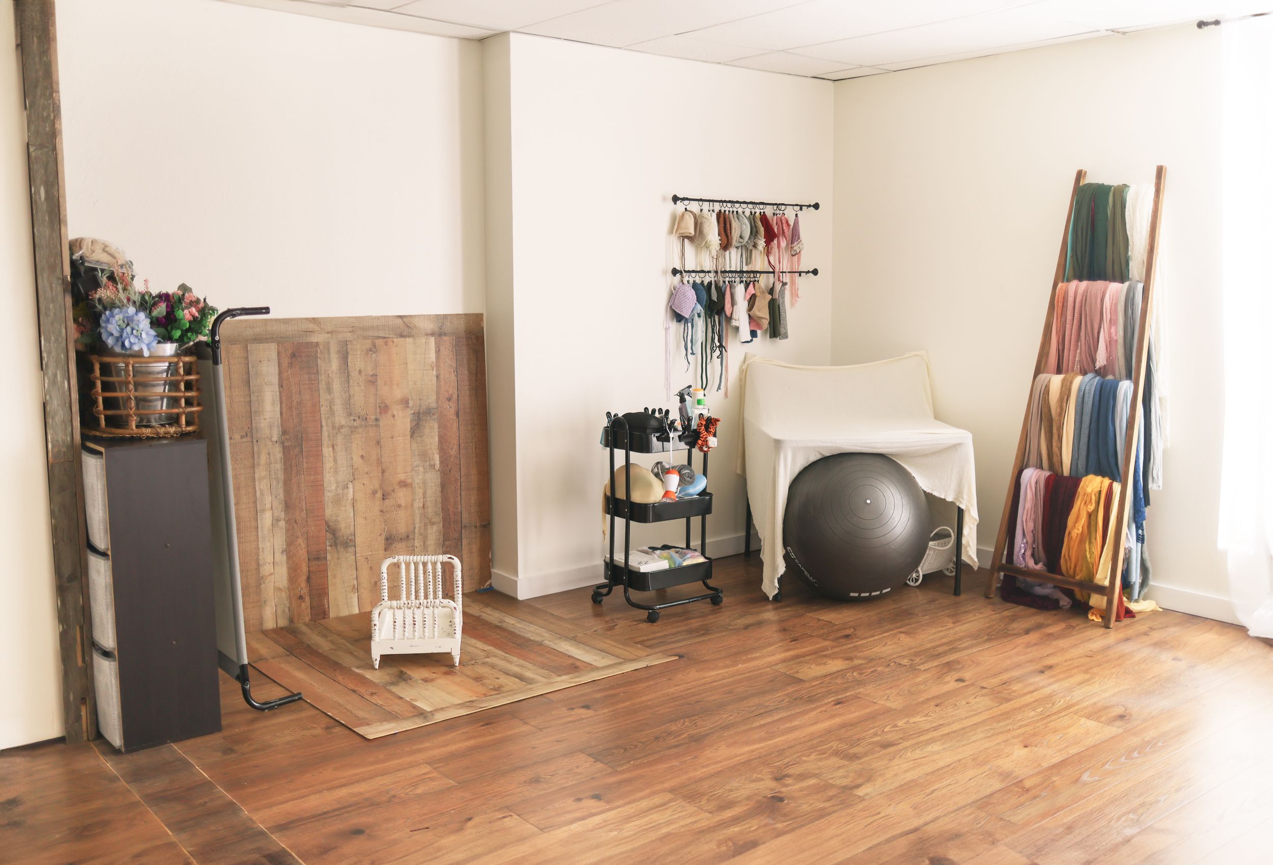 Photography studio space with wooden floors and various equipment and props.