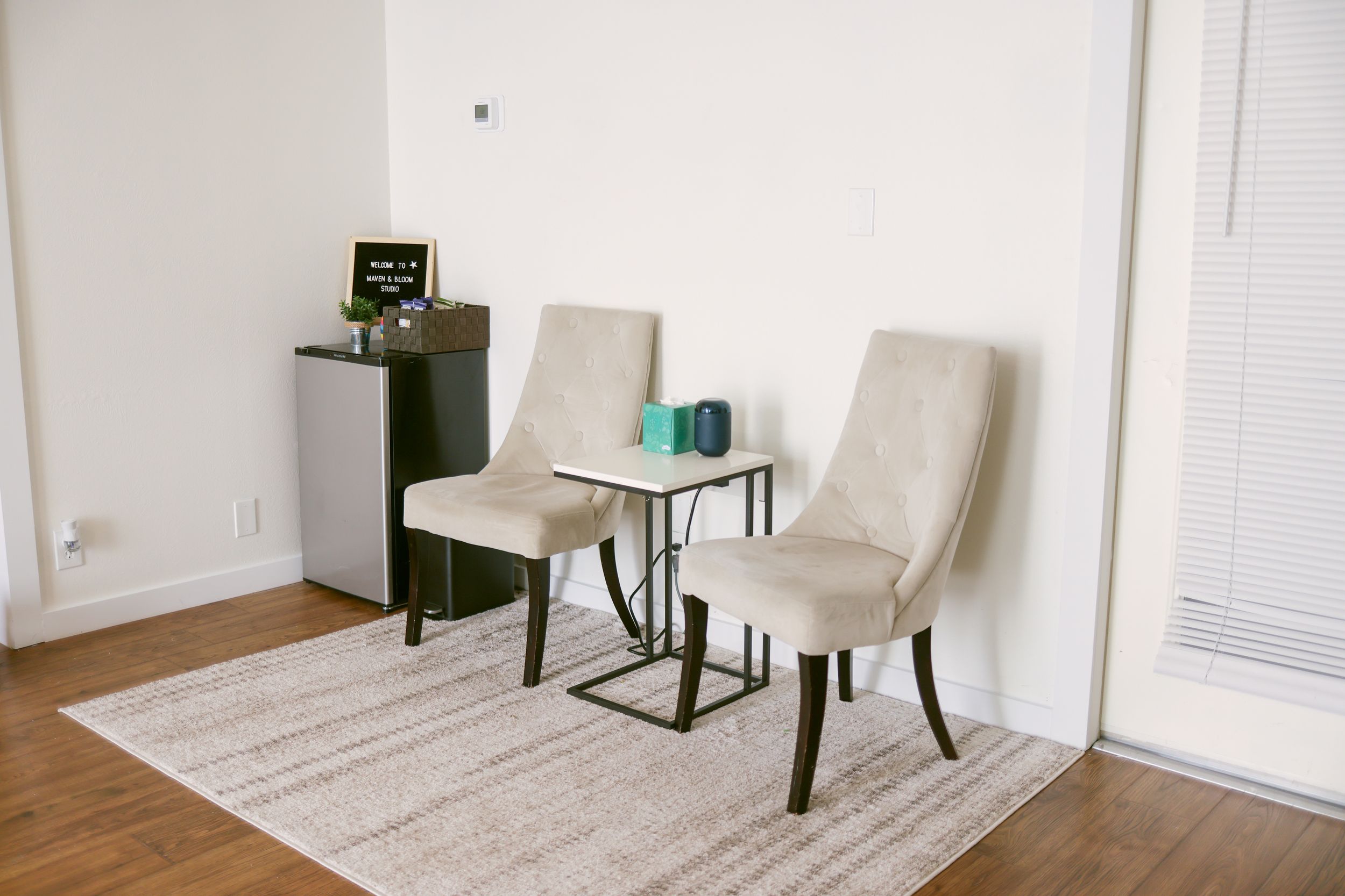Modern client meeting area with two upholstered chairs and small table.
