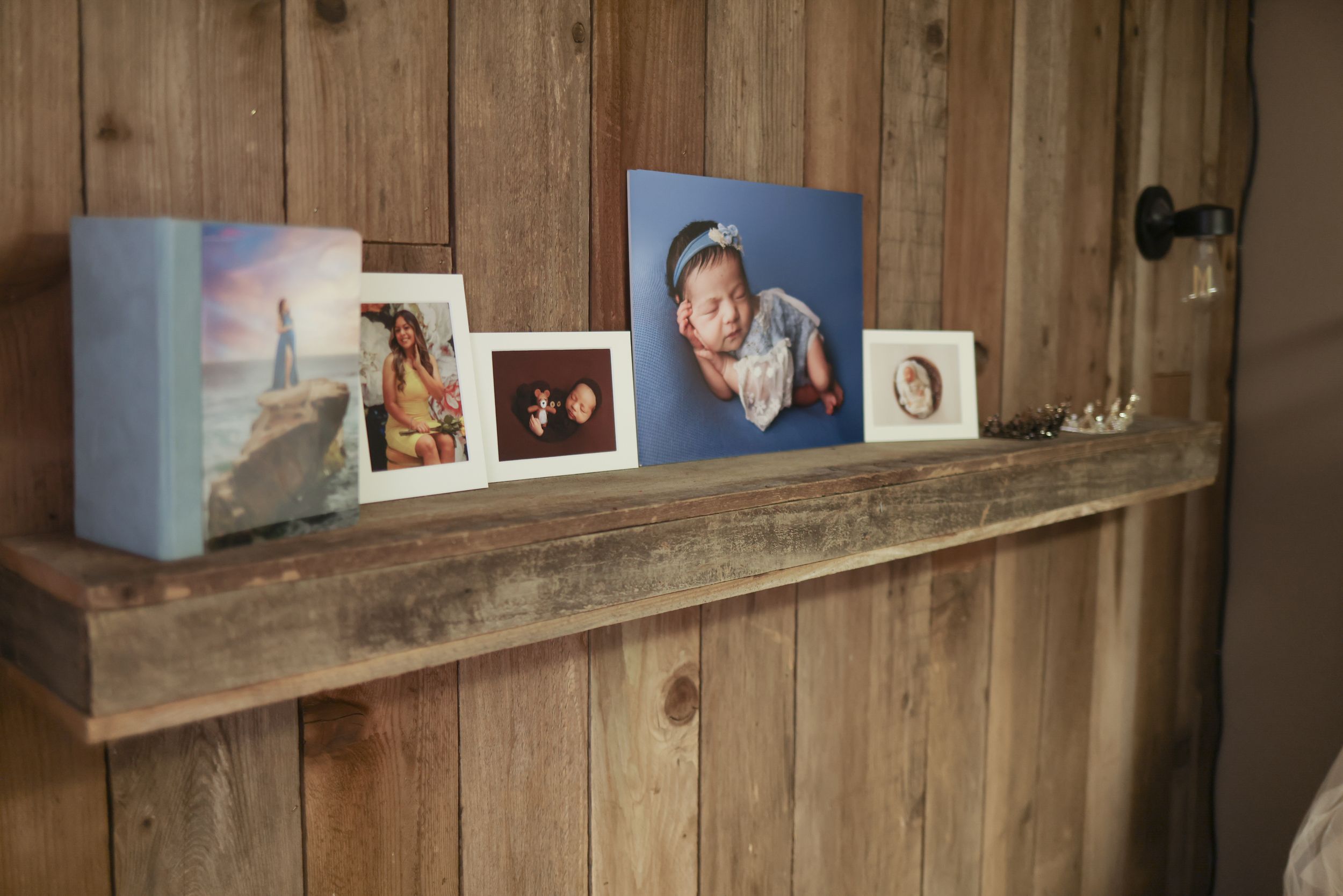 Rustic wooden shelf displaying various framed photographs.