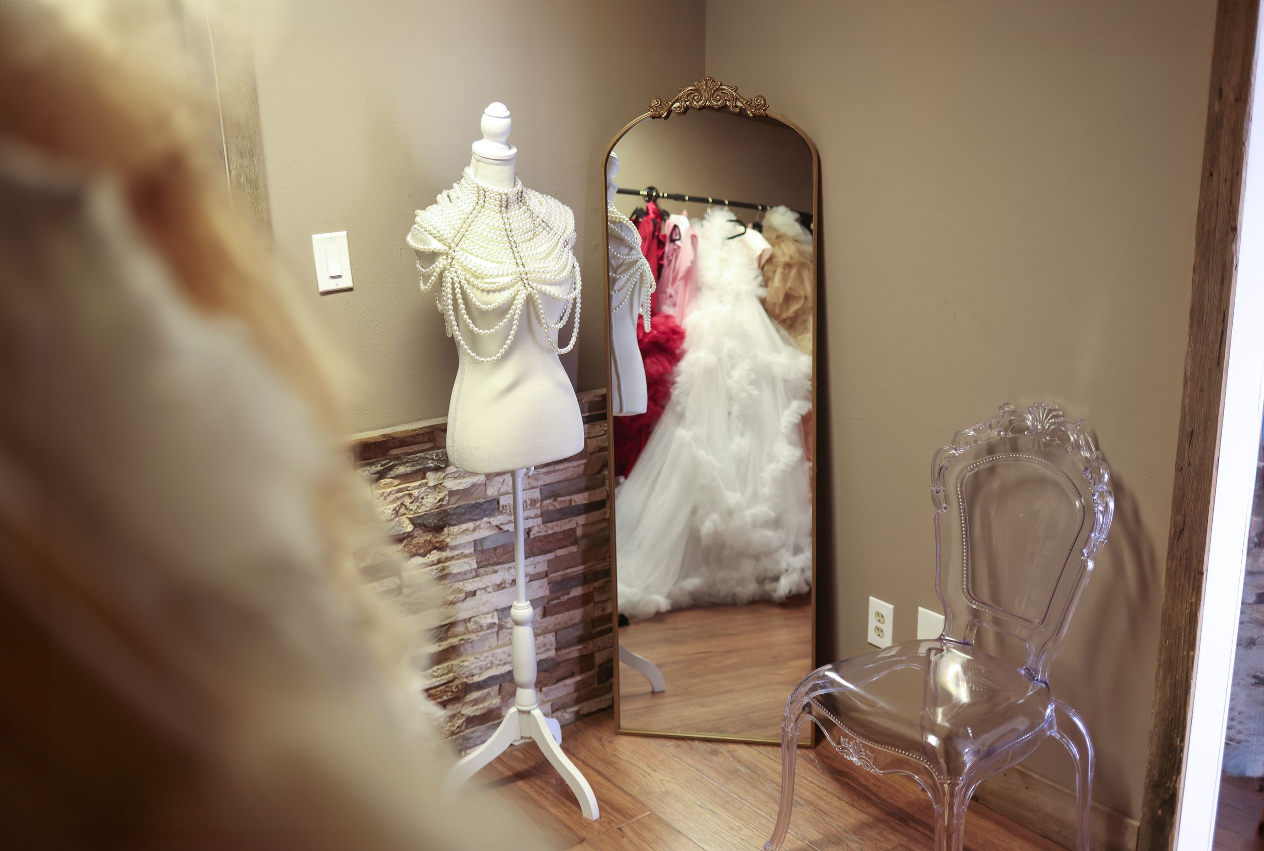 Bridal fitting room with mannequin and mirror reflecting wedding dresses.