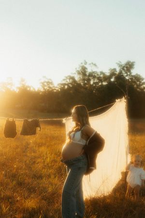 Golden sunset illuminates a dreamy countryside scene with laundry hanging on clothesline in a rustic field.