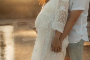 Couple in white outfits hold hands during golden hour sunset on a beach in romantic soft focus shot.