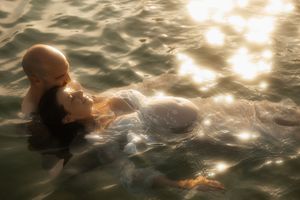 A person floats peacefully in shimmering water at sunset with golden light reflecting off gentle ripples.