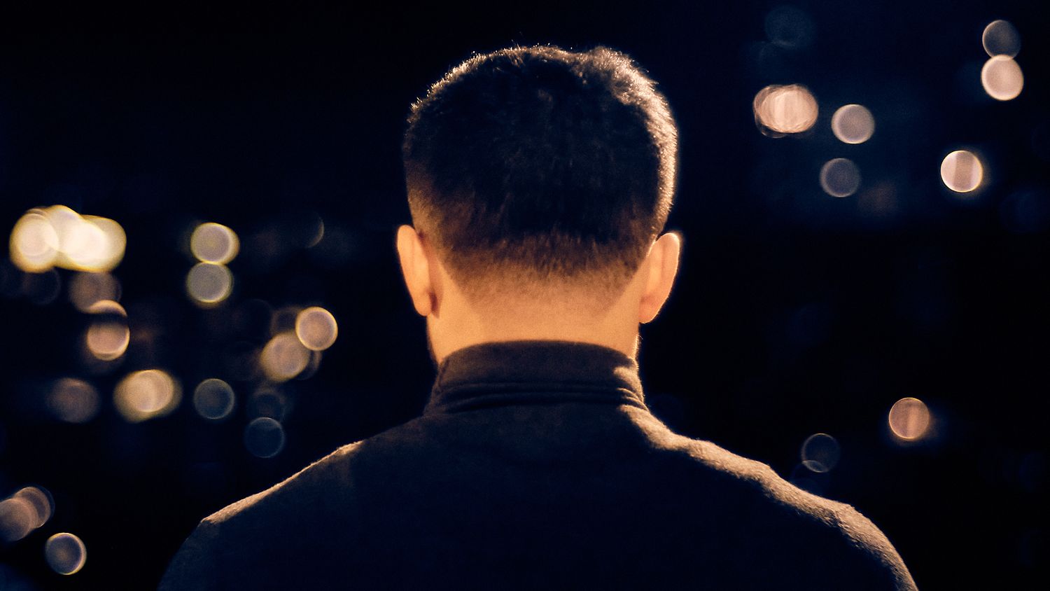 Silhouette of a person against blurred city lights at night.