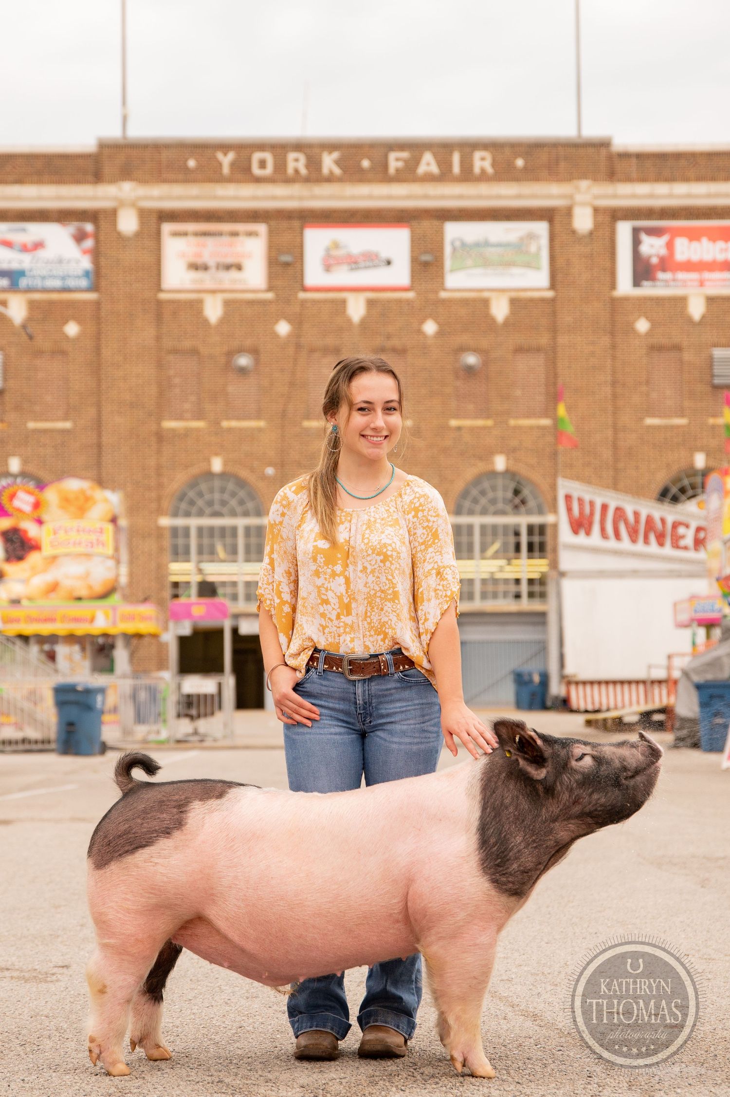 A show pig and handler pose in front of the York Fair building entrance.