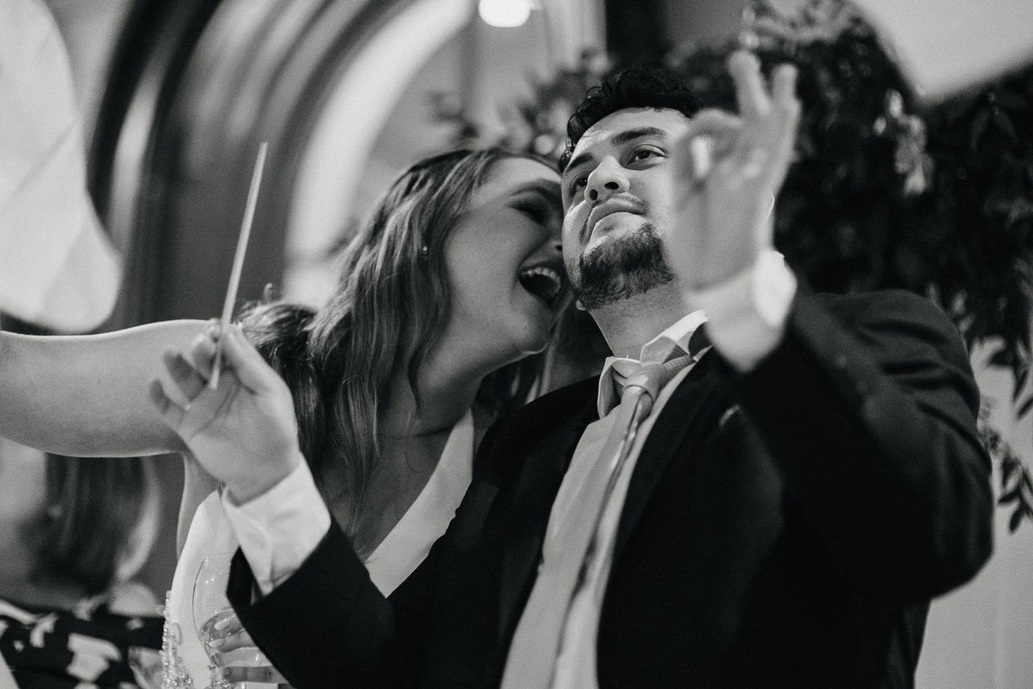 Black and white candid moment of joyful dancing at a wedding reception.