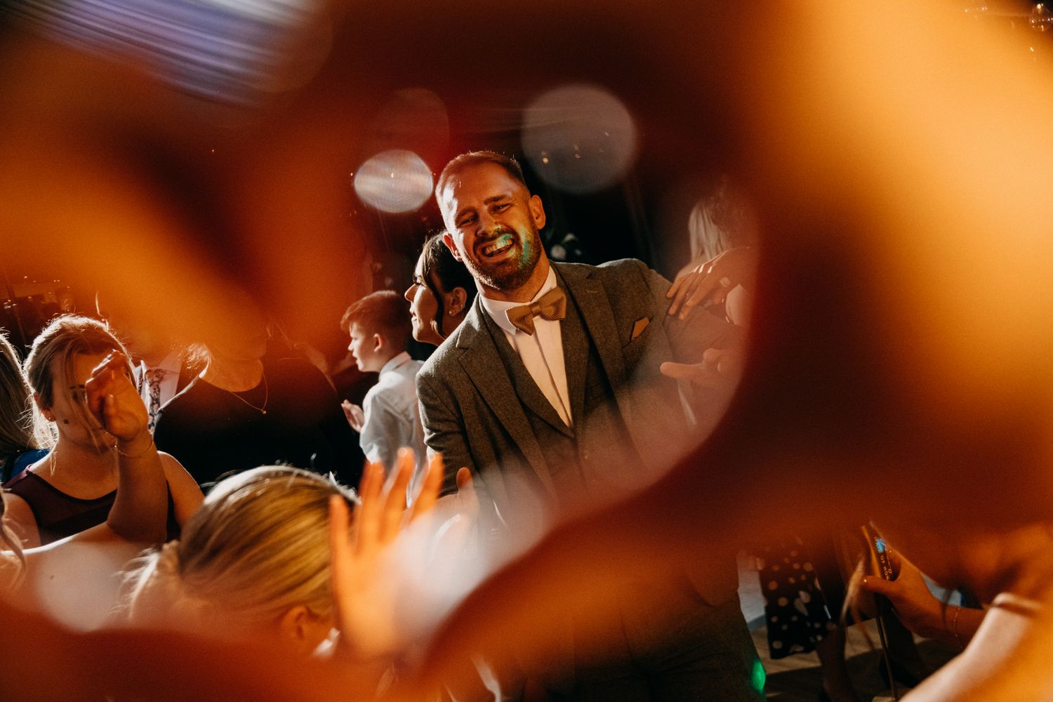 Warm-toned photo of wedding reception dance floor celebrations.