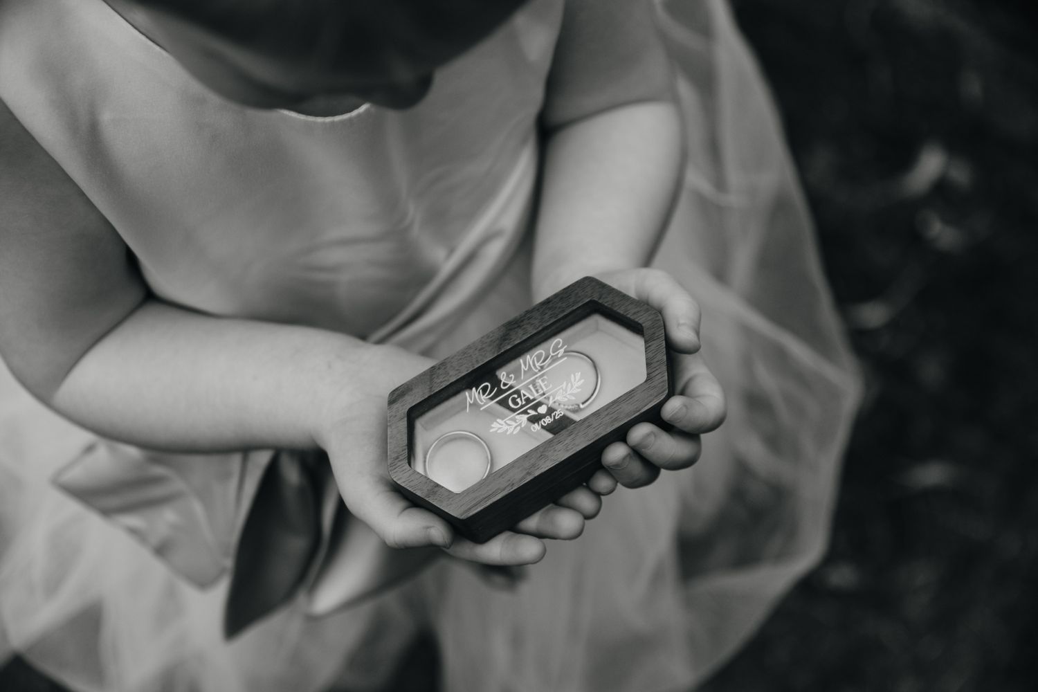 Black and white close-up photo shows a hand holding a mobile phone, casting dramatic shadows across the frame.