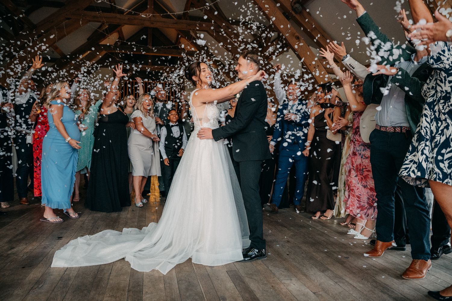 Wedding celebration with guests throwing rice and sparklers as couple exits through illuminated nighttime walkway.
