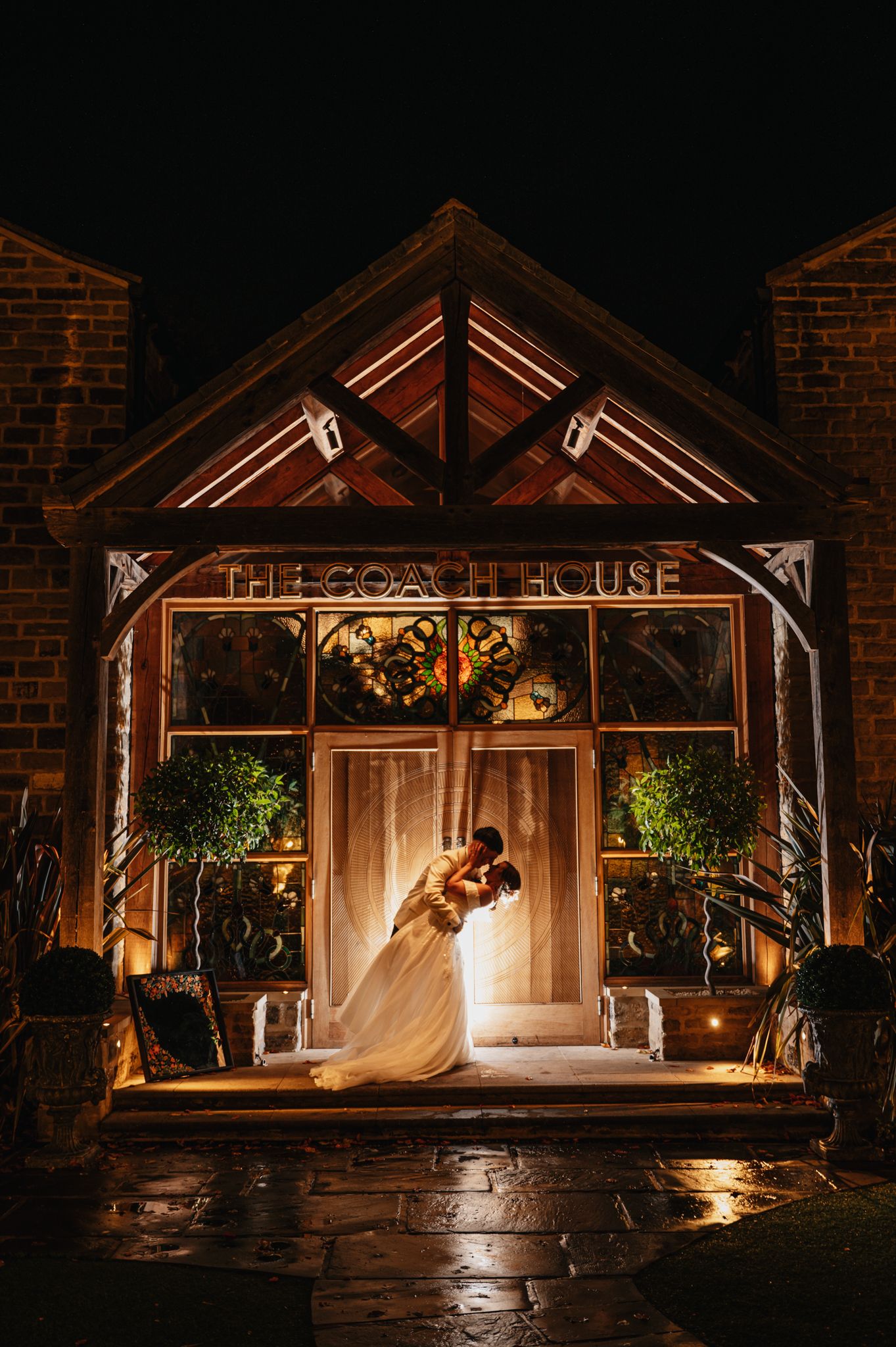 A romantic nighttime wedding scene in an illuminated brick gazebo with glowing lights and dramatic shadows.
