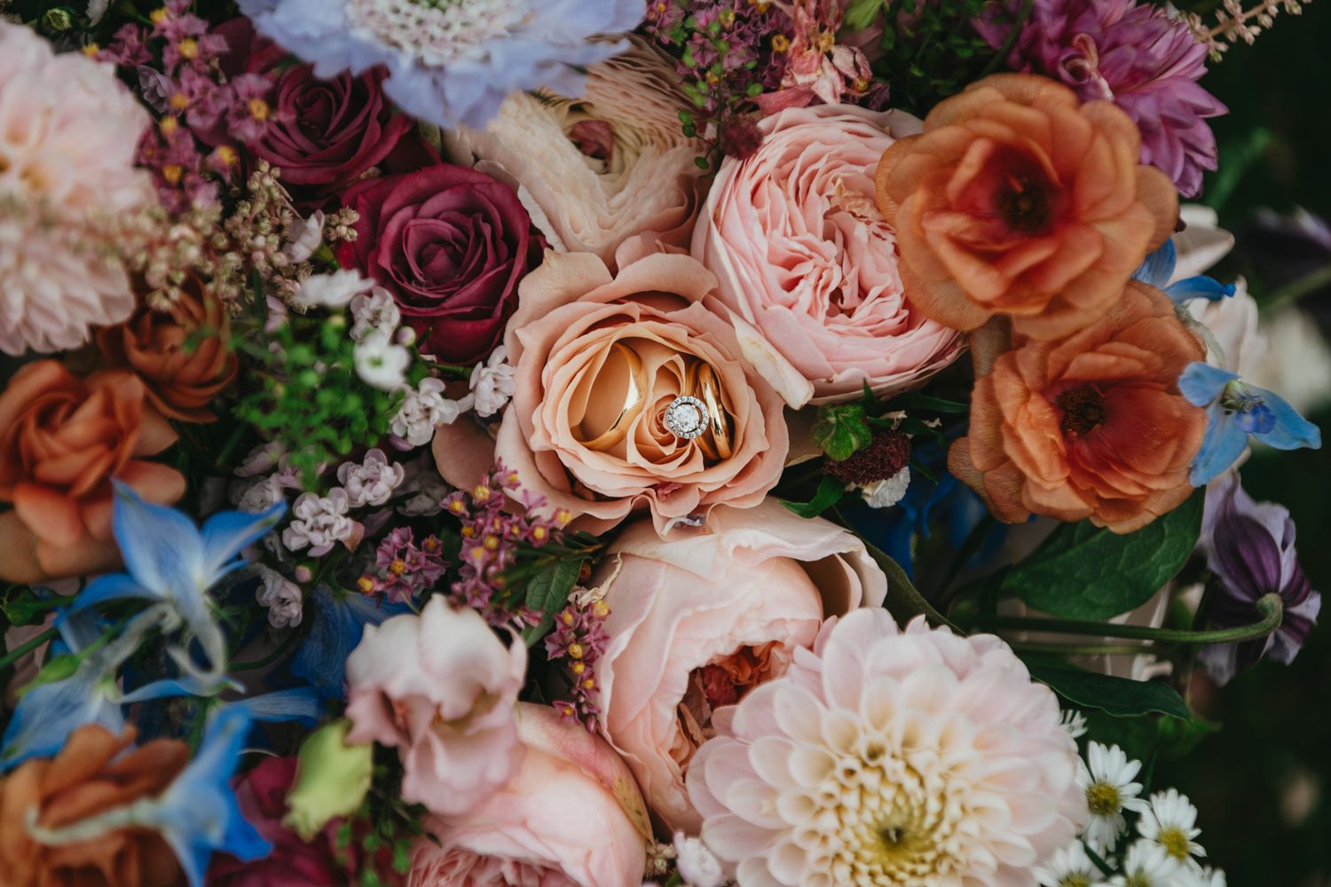Close-up of luxurious wedding bouquet with pink, peach and burgundy roses.