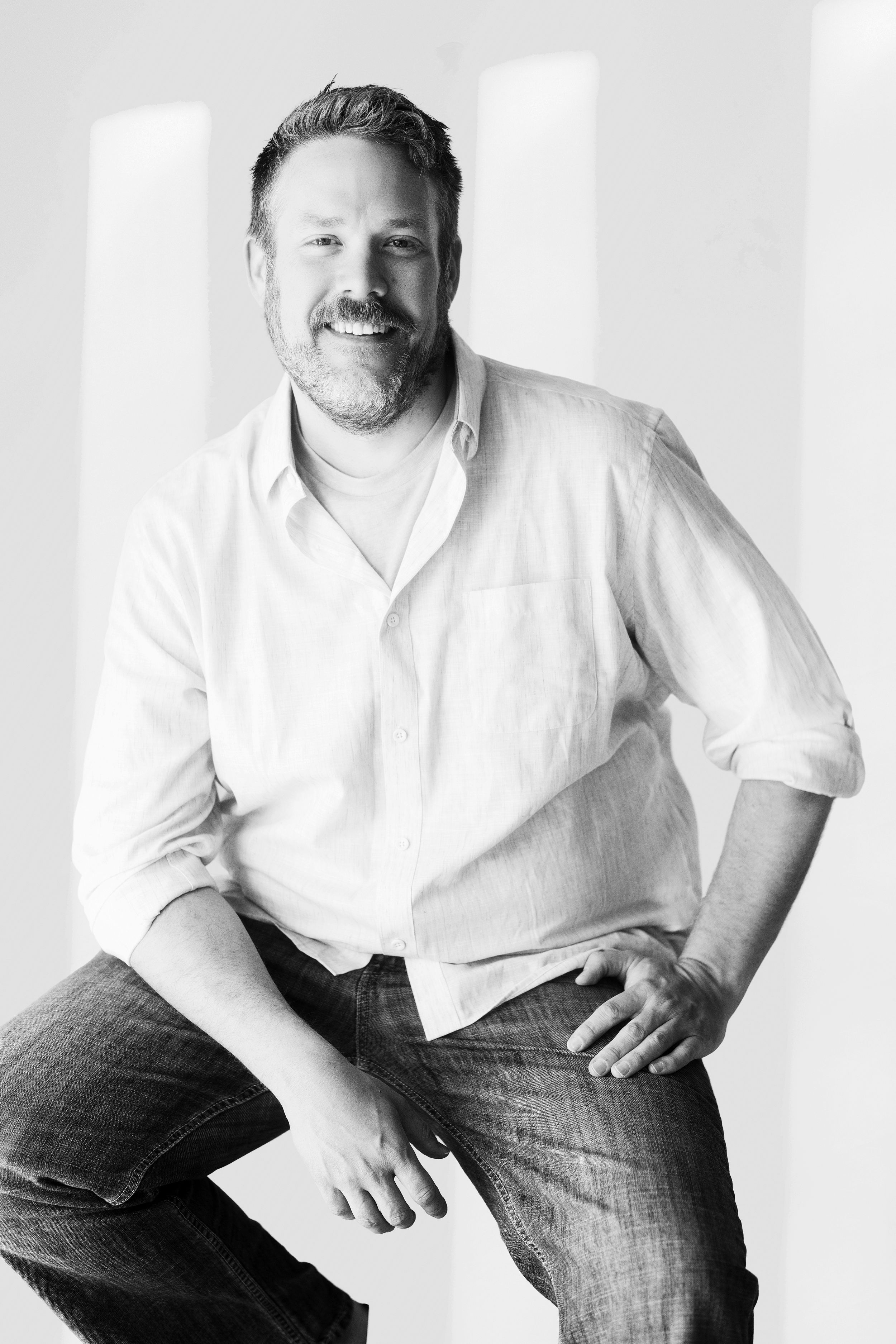 Professional black and white portrait series showing casual seated poses against a light background.