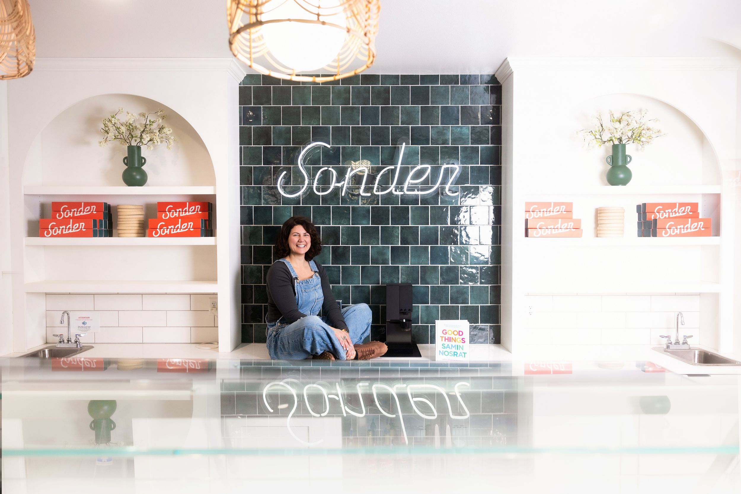 Interior of Sonder cafe with green tiled wall, white arched alcoves, and glass display counter.
