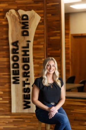 Professional setting with wooden wall decor displaying Medora West-Roehl DMD signage.