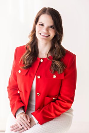 Person wearing bright red blazer with gold buttons poses for professional headshots.