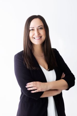 Professional headshot of a woman in business attire against a white backdrop.