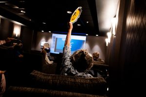 A series of four low-light photos showing someone holding up a glowing yellow disc in a dark room.