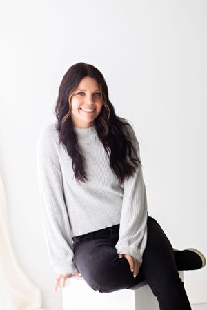 Professional studio portrait of a woman in a light sweater against a white background.