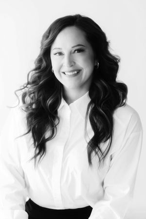 A series of four black and white headshots featuring someone with dark wavy hair wearing a white top against a light background.