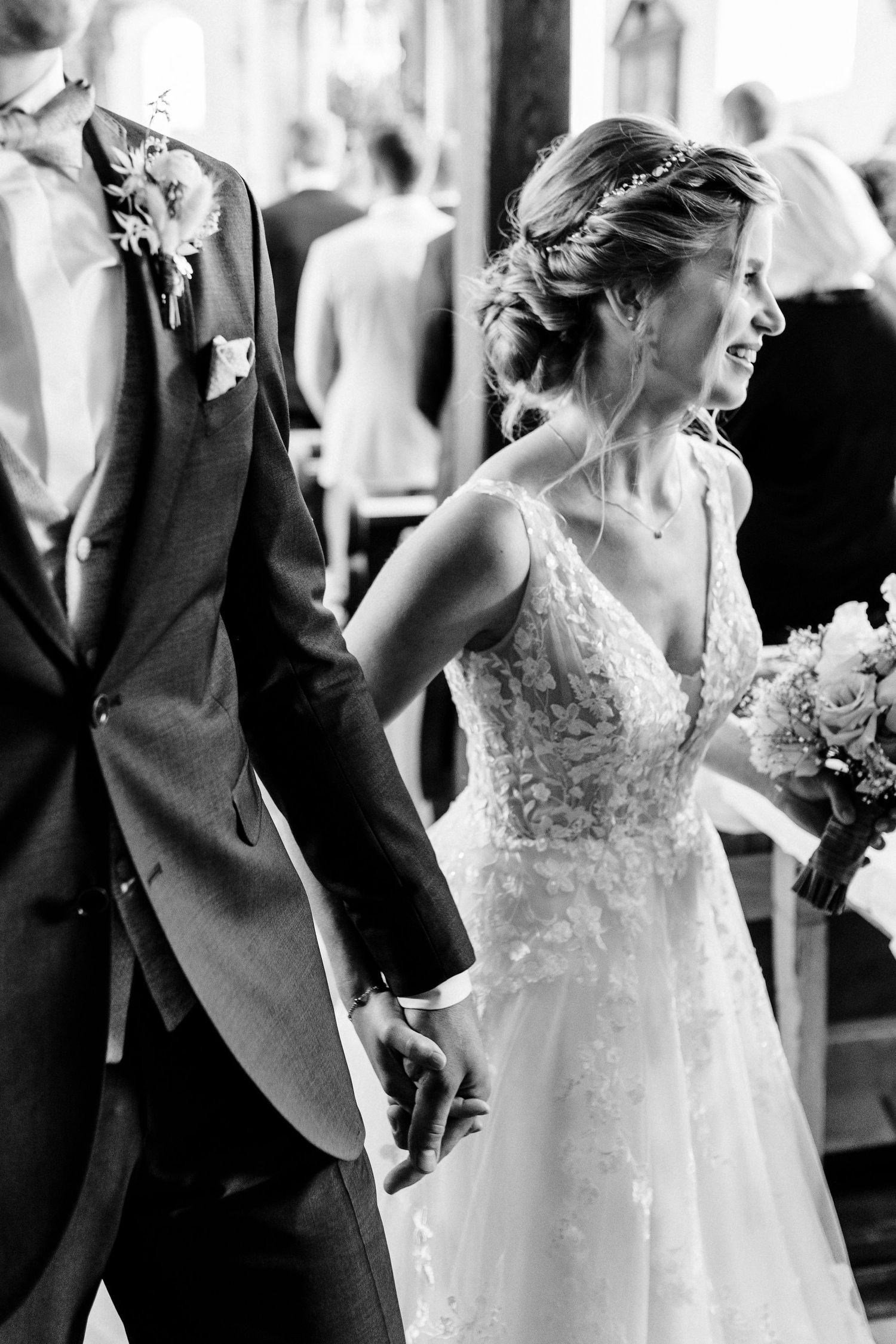 Black and white photo of a bride in a lace gown and groom in a classic suit sharing a joyful moment during their ceremony.