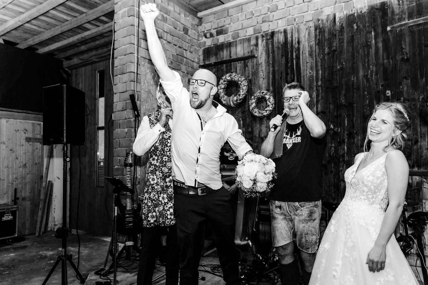 Black and white celebration shot of wedding reception party with joyful dancing.