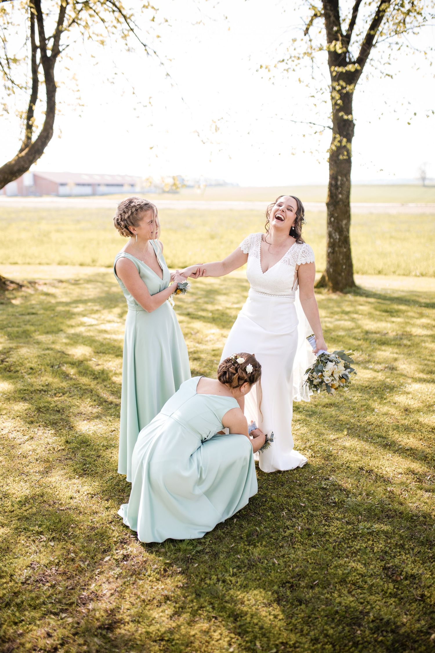 Candid moment of laughter and dress adjustments in a sunny field.
