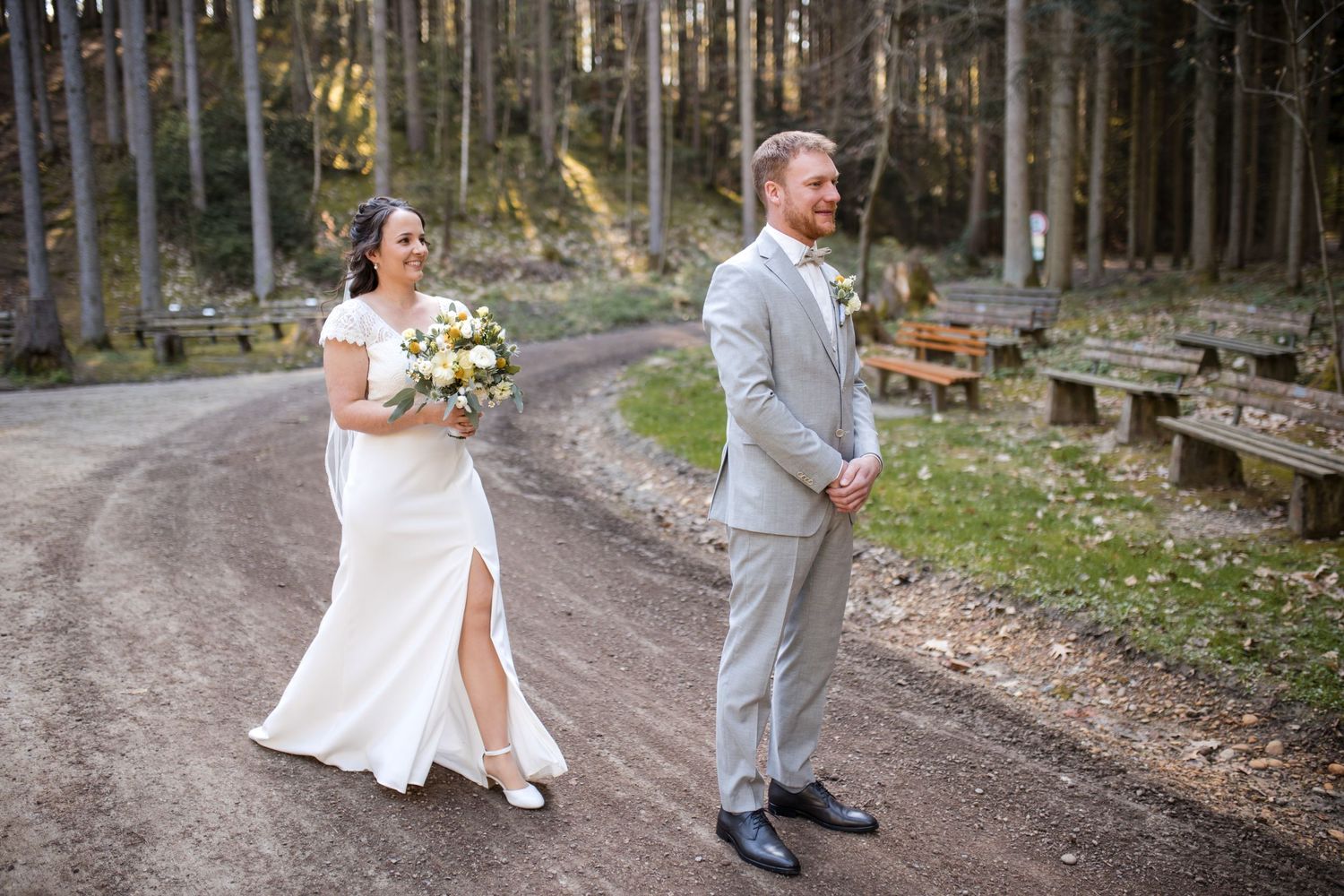 Playful first look moment between couple on forest path.