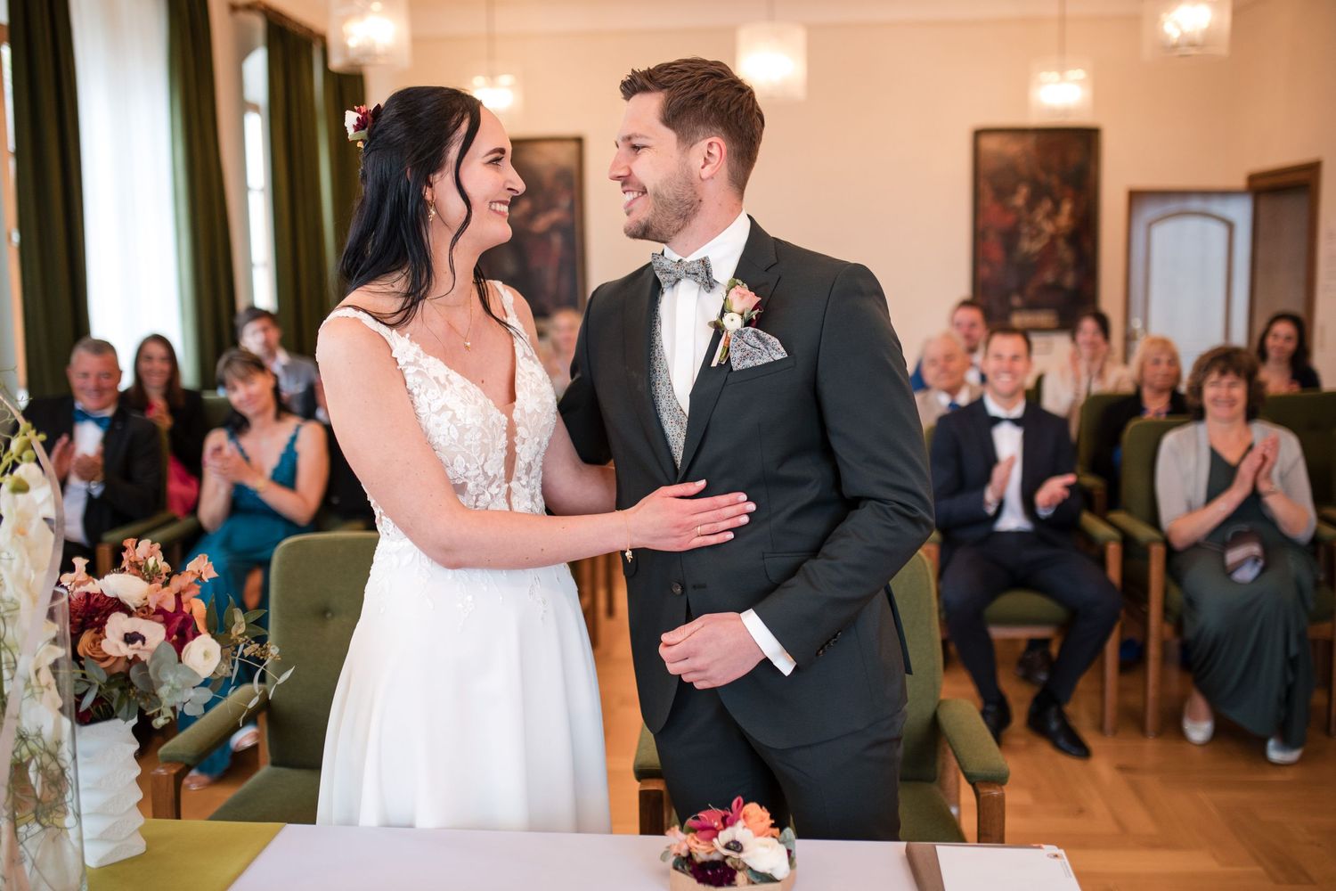 Joyful couple shares a moment during their wedding ceremony in an elegant indoor venue with guests.