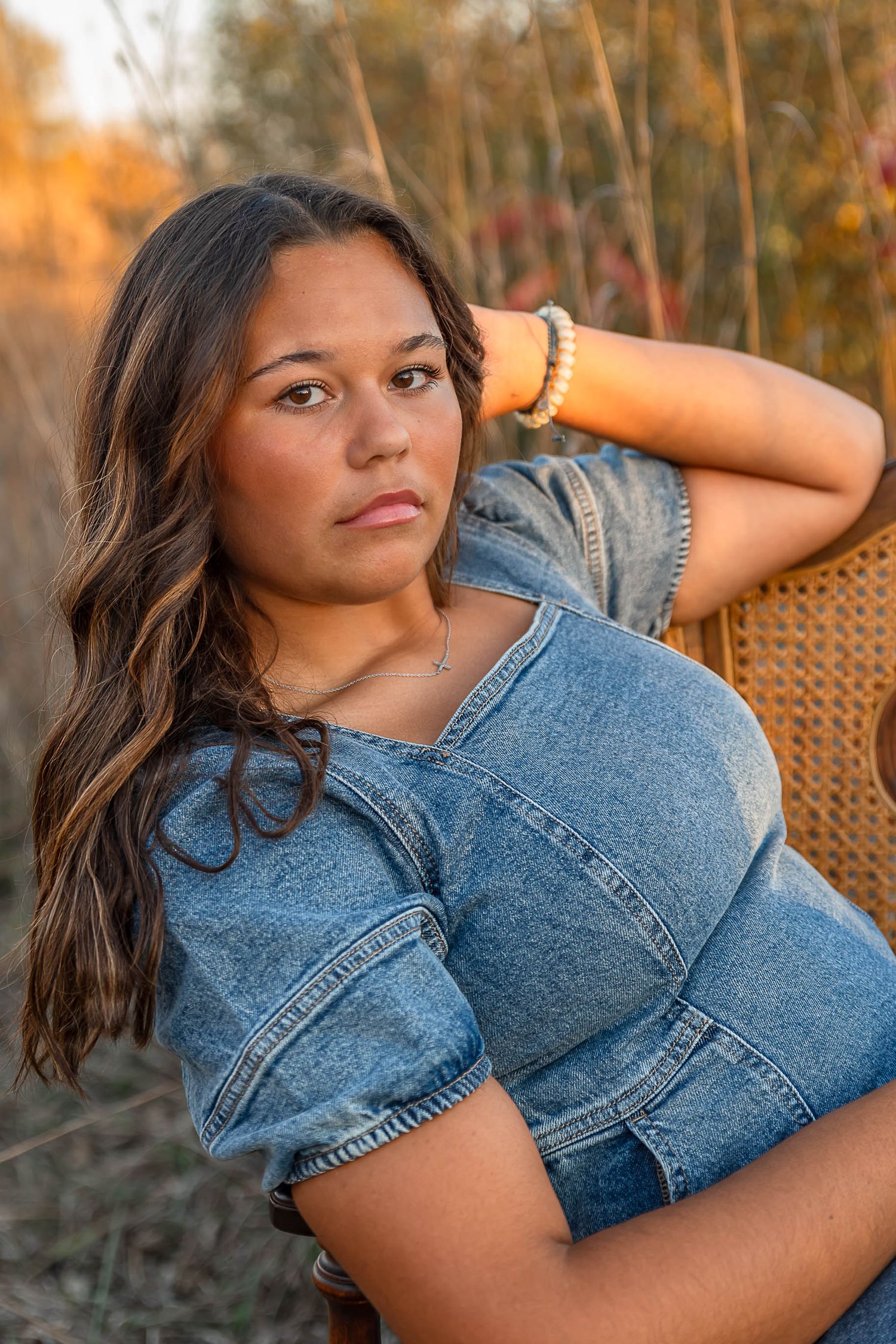 Portrait of a woman in denim outfit posing outdoors during golden hour.