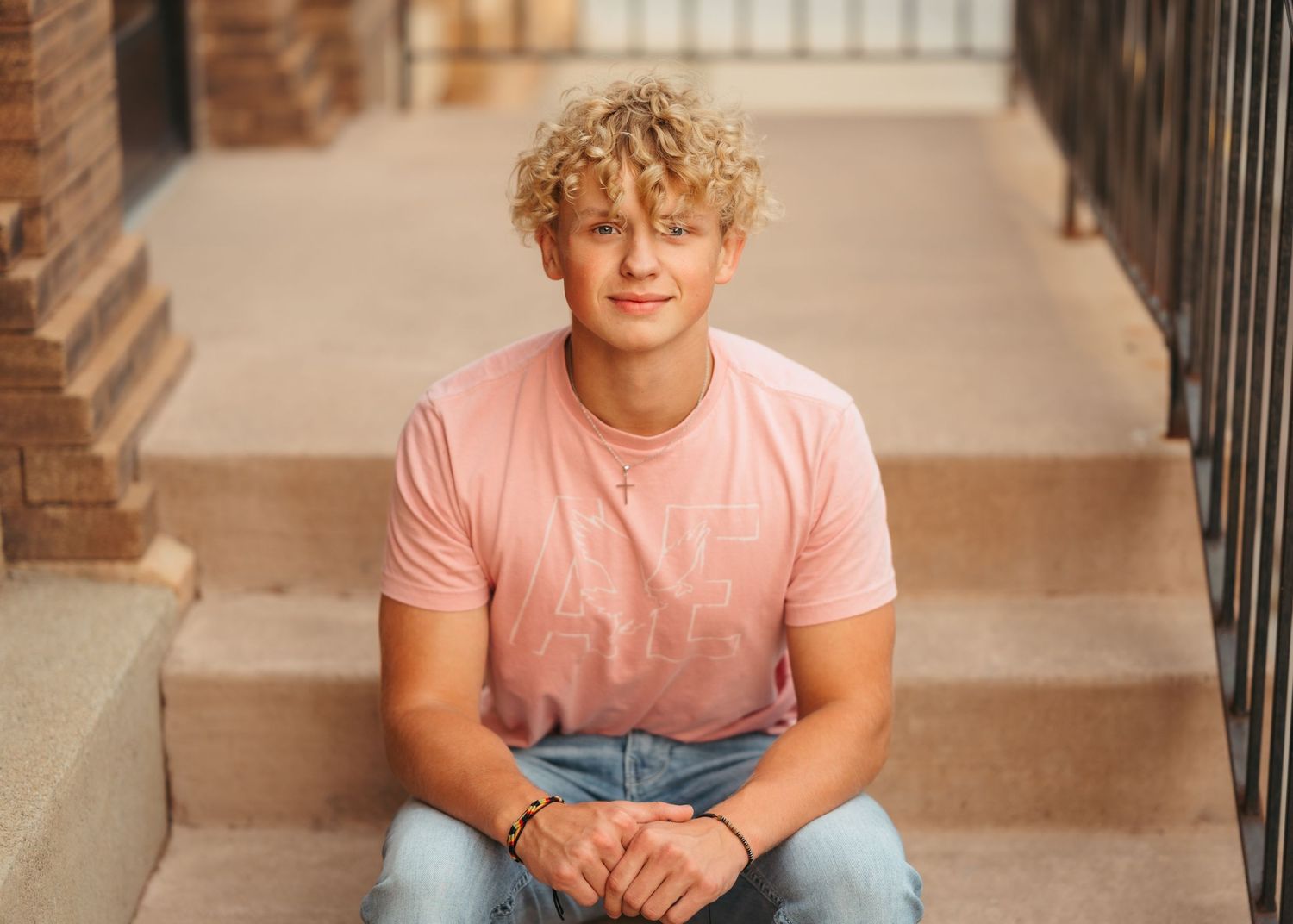 Portrait on brick steps with person in pink shirt and jeans.