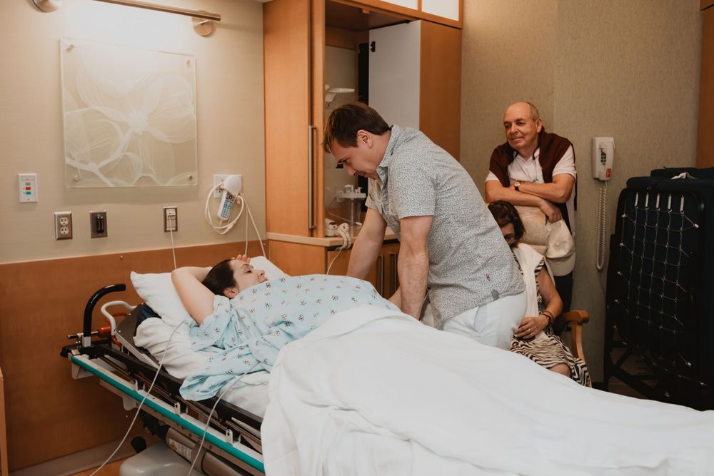 Medical team providing care in hospital room with monitoring equipment.