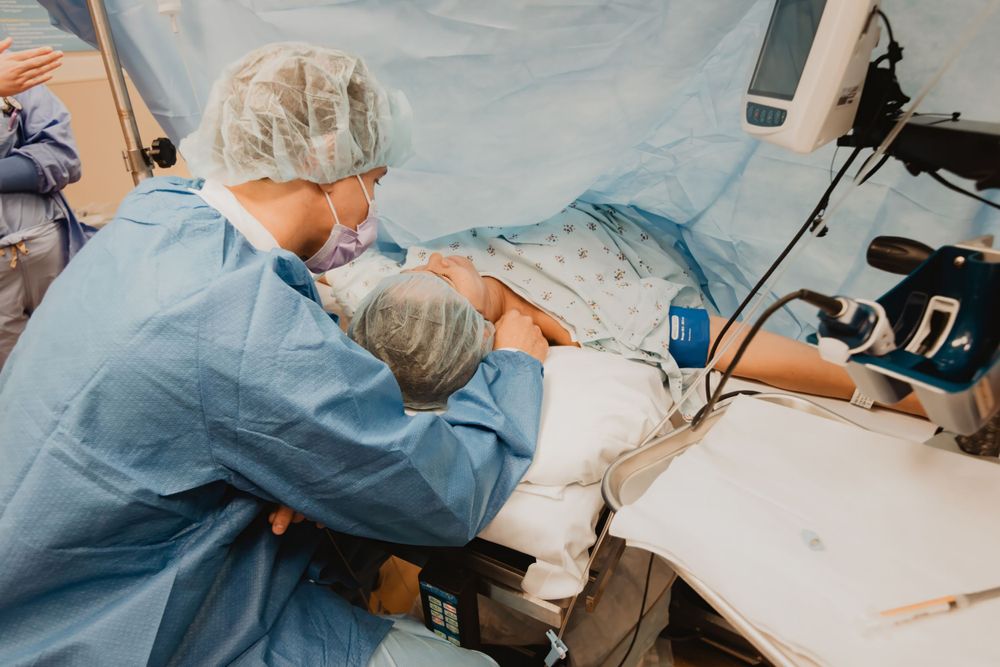 Healthcare provider in blue scrubs and protective gear performs a medical procedure in a clinical setting.