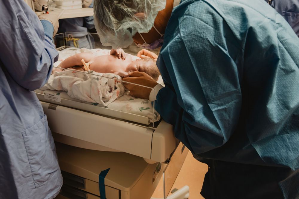 Medical staff in protective equipment perform careful examination in a hospital setting.