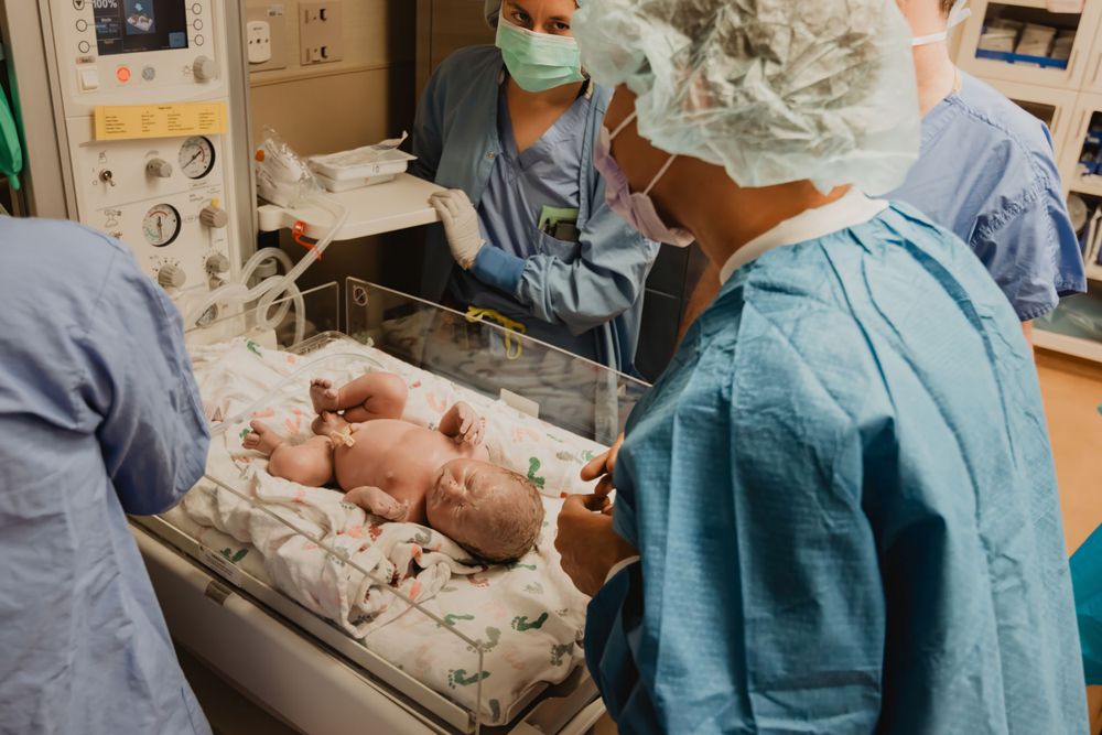 Healthcare professionals in surgical attire perform medical care in a hospital environment.