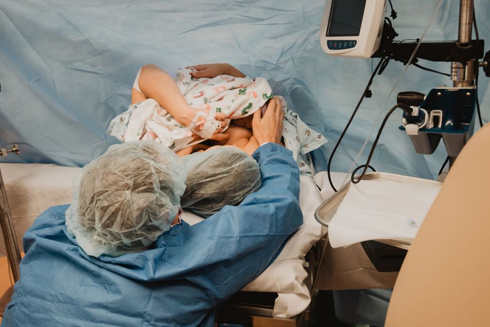 Healthcare worker in surgical attire performs detailed medical work in a clinical environment.