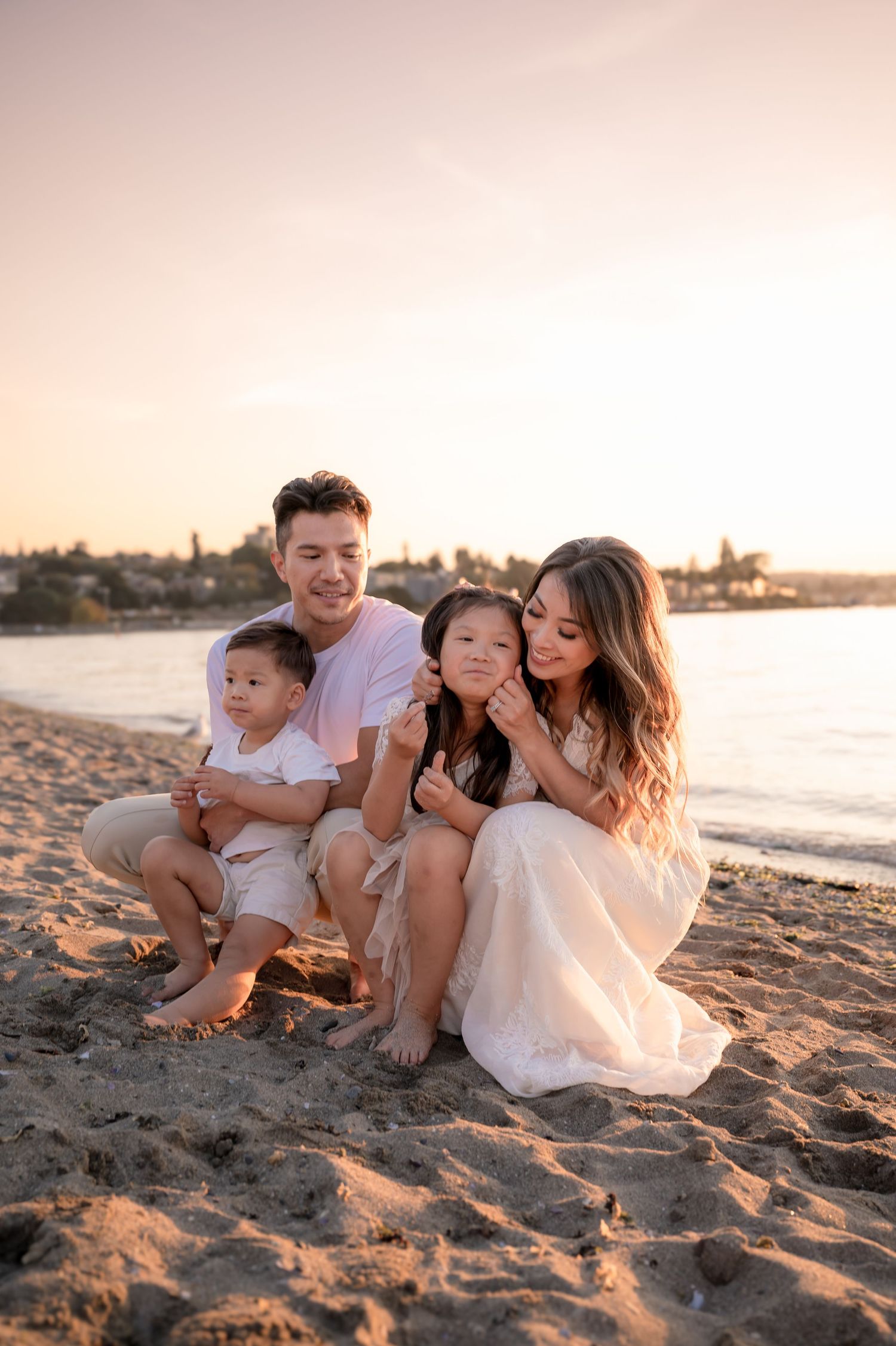 A family sitting together on sandy beach during golden hour sunset.