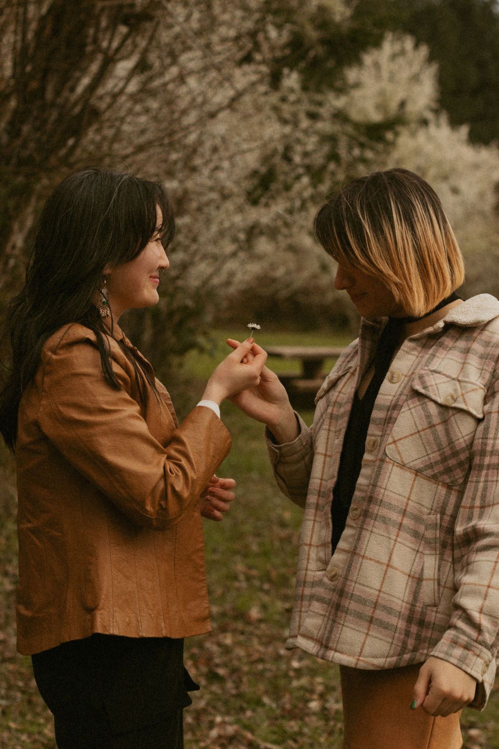 Couple in casual autumn outfits sharing playful moments outdoors in warm golden light.